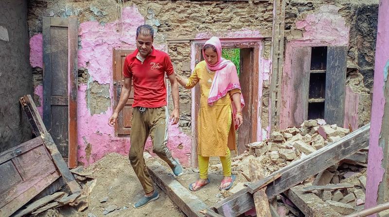 Bhaderwah: 7-month pregnant Nishu walks through the rubble of her mud house, in Bhaderwah. (PTI Photo)