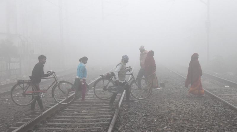 Patna: Commuters cross railway tracks amid fog on a cold winter morning, in Patna, Friday, Dec. 29, 2023. (PTI Photo)