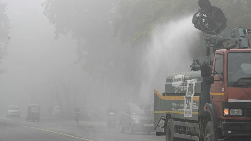 New Delhi: A municipal truck sprays water on a roadside to suppress dust and pollution amid dense foggy conditions, in New Delhi, Monday, Dec. 15, 2025. (PTI Photo)