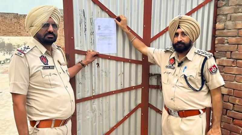 ਪੁਲਿਸ ਨਸ਼ਾ ਤਸਕਰ ਦੇ ਘਰ ਦੇ ਬਾਹਰ ਨੋਟਿਸ ਲਗਾਉਂਦੀ ਹੋਈ 