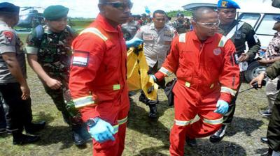 Indonesian military and police officers carry body bags