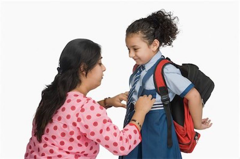 Woman preparing her daughter for school