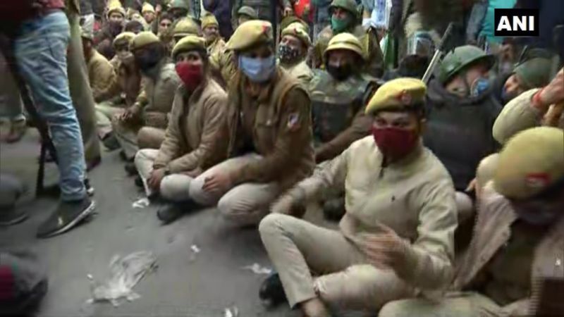 Police officials sit on road to block area where farmers holding tractor parade